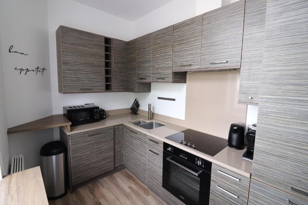 a kitchen with wooden cabinets and a black appliance at The Windsor Club Apartment in Leamington Spa