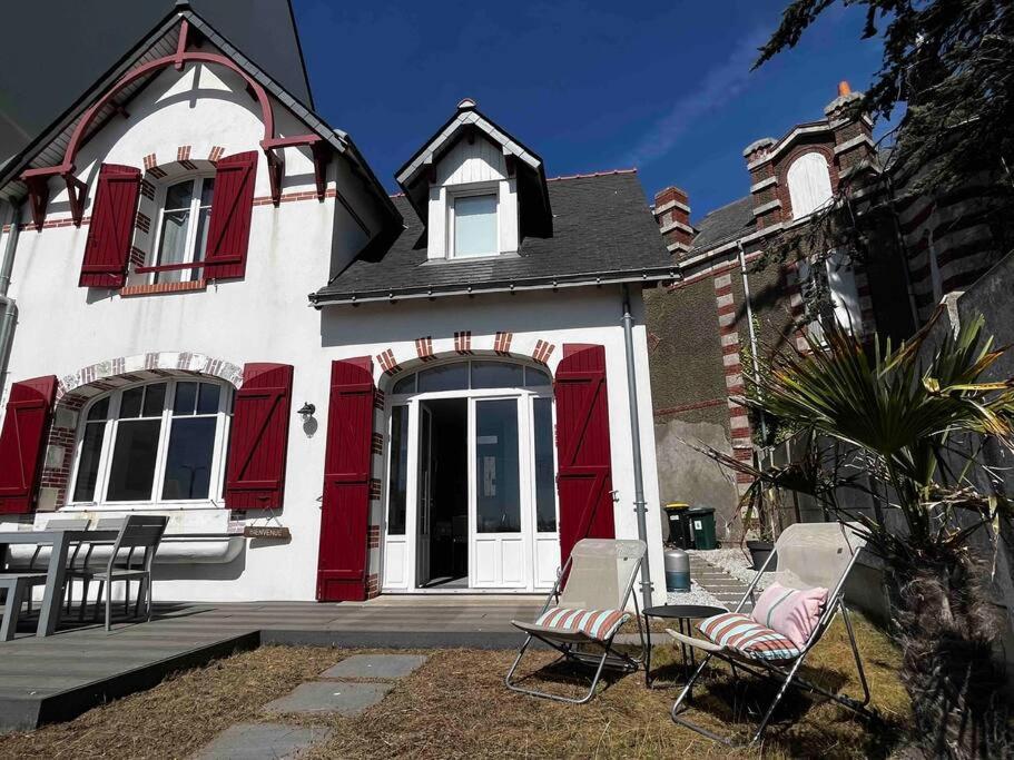 une maison avec des portes rouges et des chaises devant elle dans l'établissement Pornichétine pour 8 personnes face à l'océan et à 100m du marché, à Pornichet