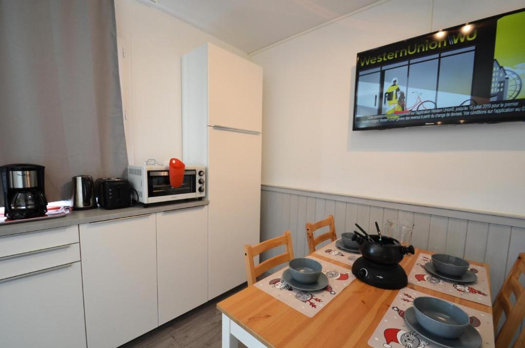 a kitchen with a table and chairs and a kitchen with a tv at Résidence Villaret - Studio pour 4 Personnes 194 in Les Menuires