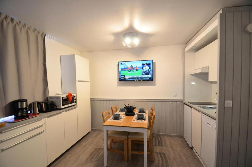 a kitchen with a table and a tv on the wall at Résidence Villaret - Studio pour 4 Personnes 194 in Les Menuires