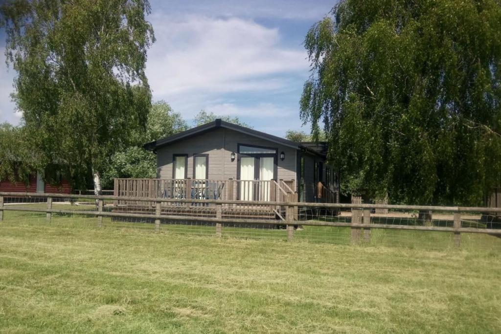 ein winziges Haus mit einer Veranda und einem Zaun in der Unterkunft Puddledock - luxury lodge - Kent countryside in Brookland