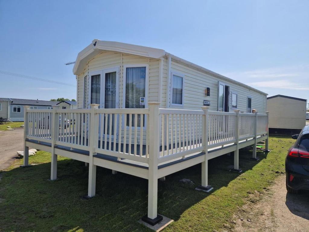 a mobile home with a porch and a fence at BH14 - Marlie Holiday Park - New Romney in Kent