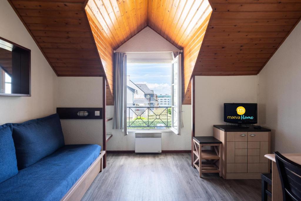 un salon avec un canapé bleu et une fenêtre dans l'établissement Résidence Port du Crouesty - maeva Home - Appartement 2 Pièces 5 Personnes avec mezzanine - Confort MAE-1844, à Arzon