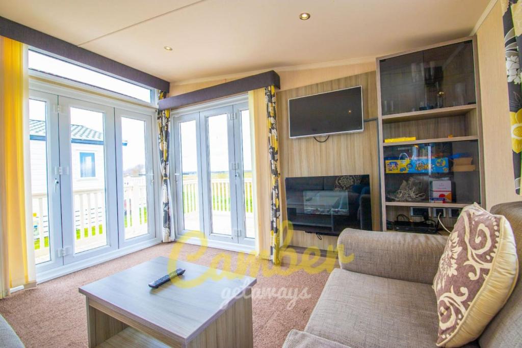 a living room with a couch and a table at MP502 - Camber Sands Holiday Park - Sleeps 6 - Small Dog - Gated Decking - Amazing Marsh Views in Camber