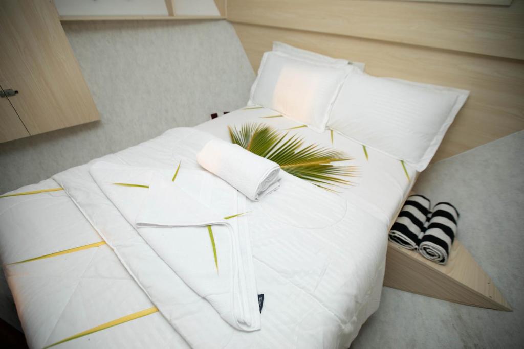una cama blanca con almohadas blancas y una planta en ella en Odyssey of sunny side, en Male
