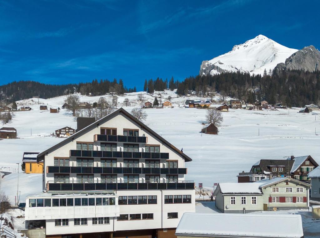un edificio con una montaña cubierta de nieve en el fondo en Hotel Toggenburg, en Wildhaus