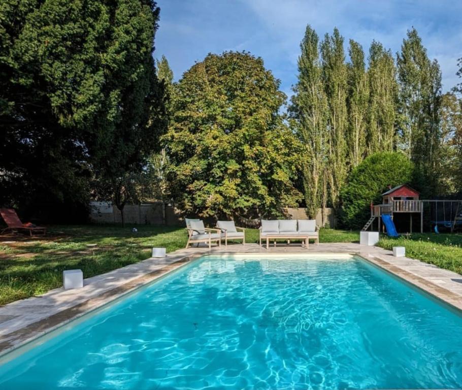 uma piscina com duas cadeiras e um banco num quintal em Maison spacieuse - Piscine - Jardin 