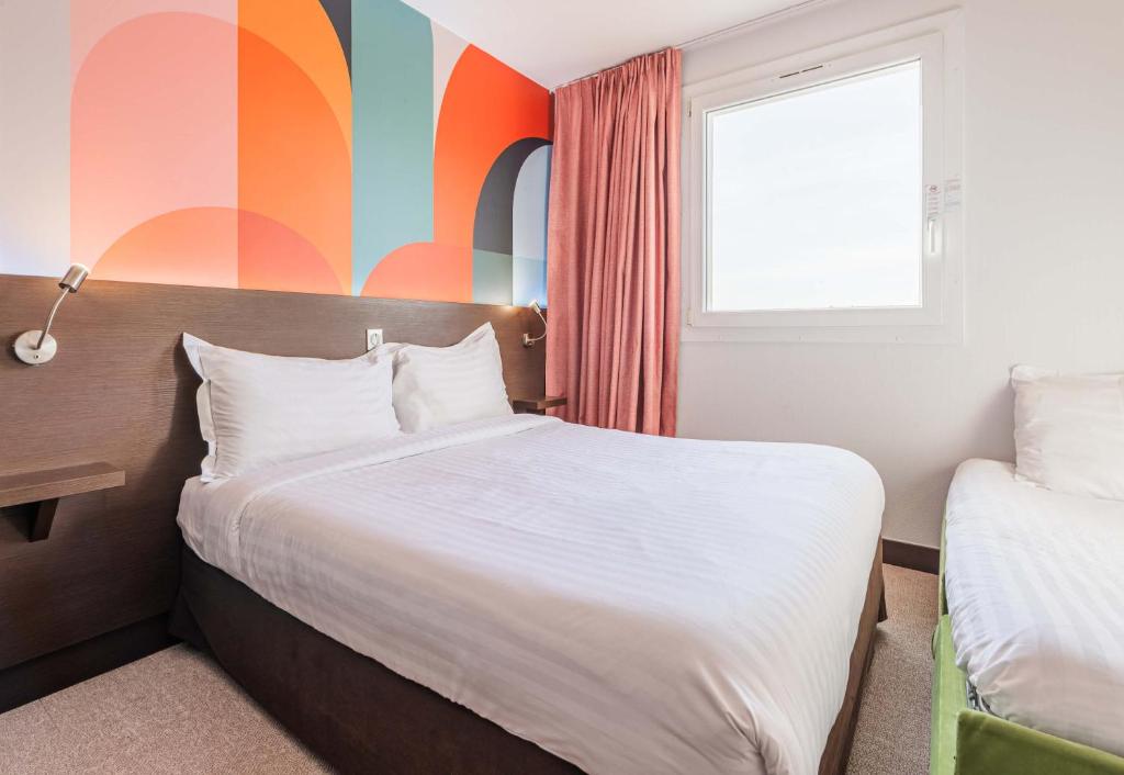 ein Schlafzimmer mit einem Bett und einer farbenfrohen Wand in der Unterkunft B&B HOTEL Colmar Liberté 4 étoiles in Colmar