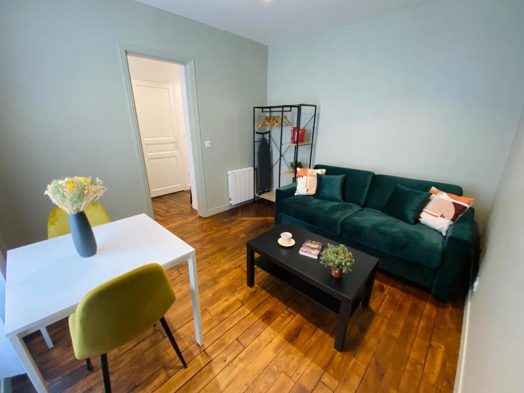 a living room with a green couch and a table at Les Appartements du Grand Hôtel Clichy Paris in Clichy