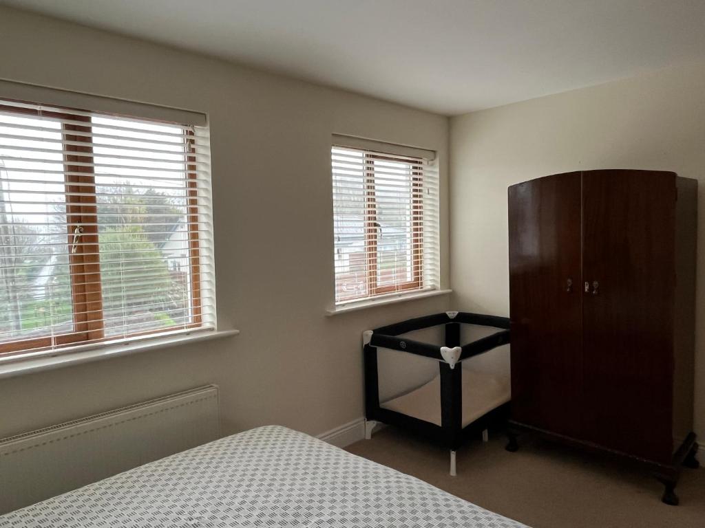 1 dormitorio con 1 cama, vestidor y 2 ventanas en Ardmore Village Family Home en Ardmore