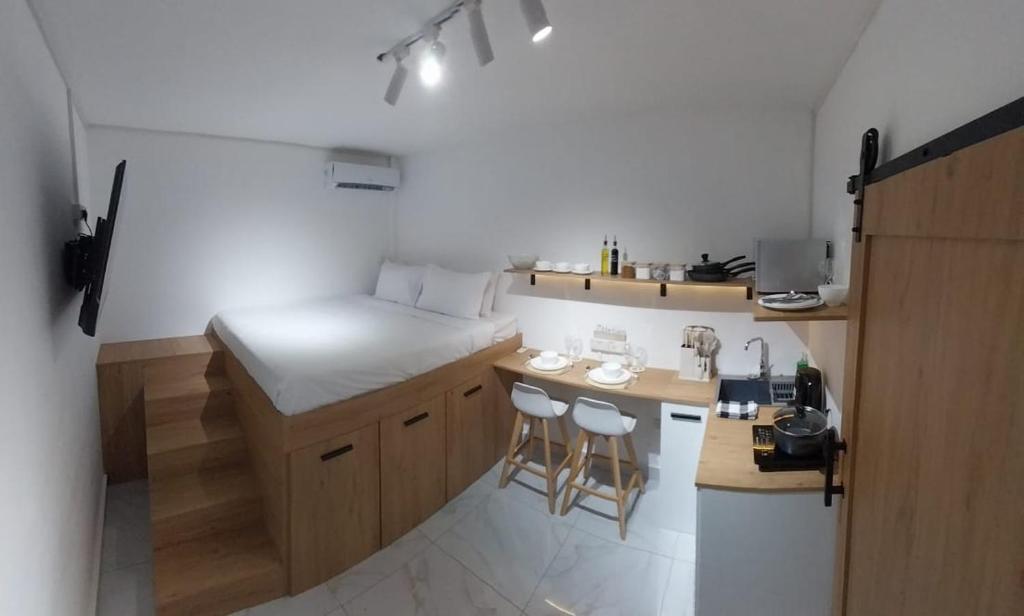 uma pequena cozinha com uma cama e um balcão com bancos em Cosy studio with all amenities em Grand Baie