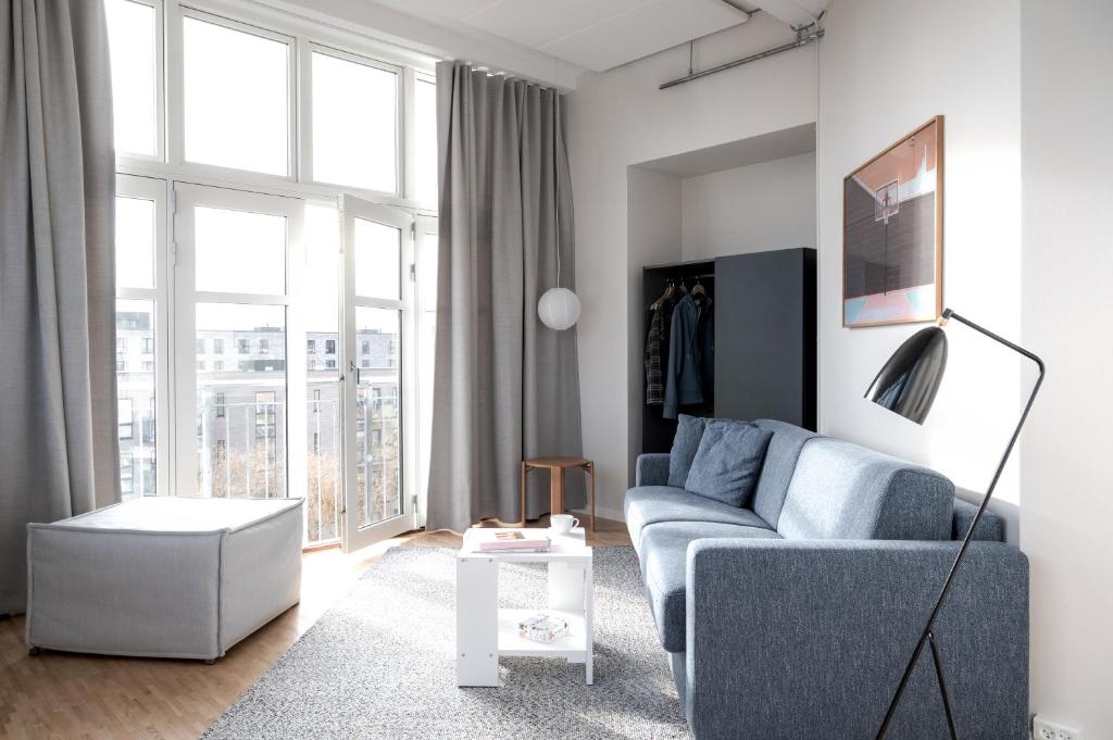 a living room with a blue couch and a large window at Beach Trail apartments by Daniel&Jacob's in Copenhagen