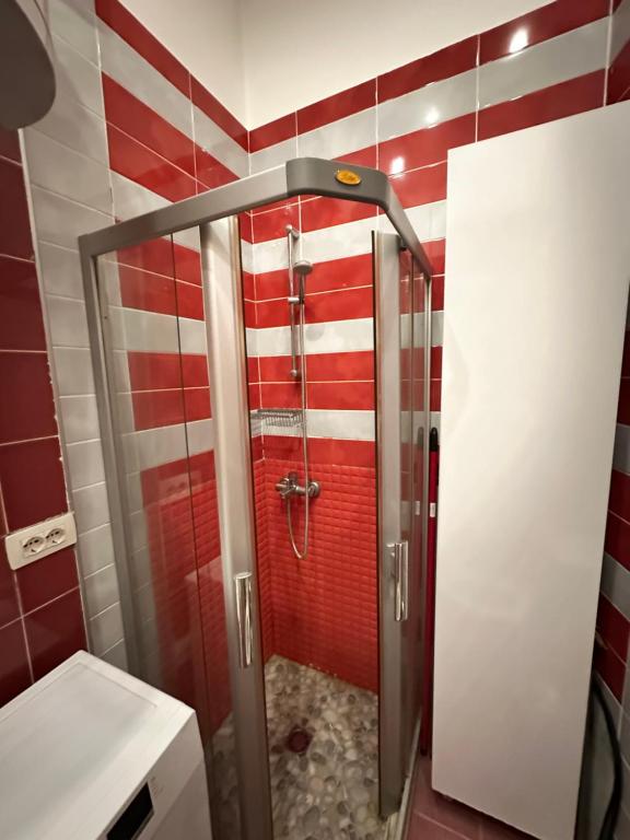 y baño con ducha y azulejos rojos y blancos. en Town Square Apartment Tirana 4 en Tirana