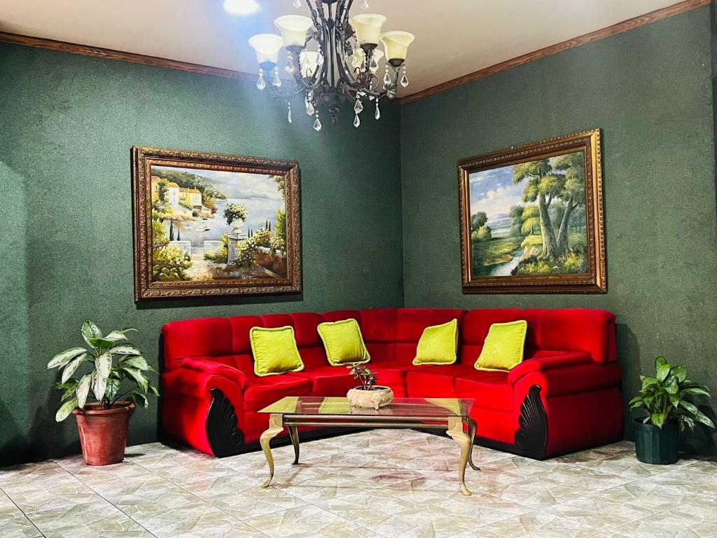 a living room with a red couch with yellow pillows at Hotel Barroco in San José