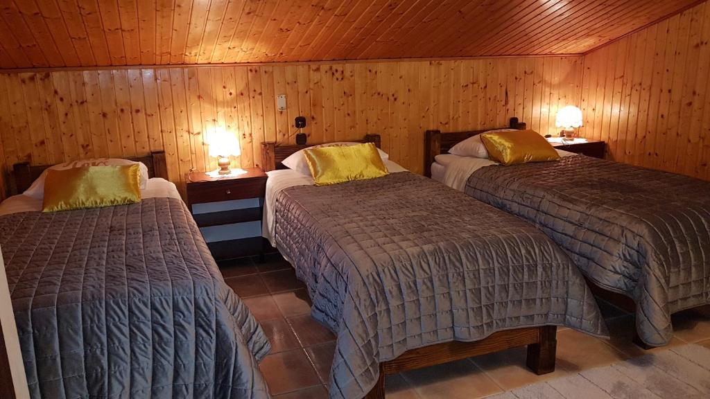 two beds in a room with wooden walls and two lamps at Rooms Marko Polo in Zadar