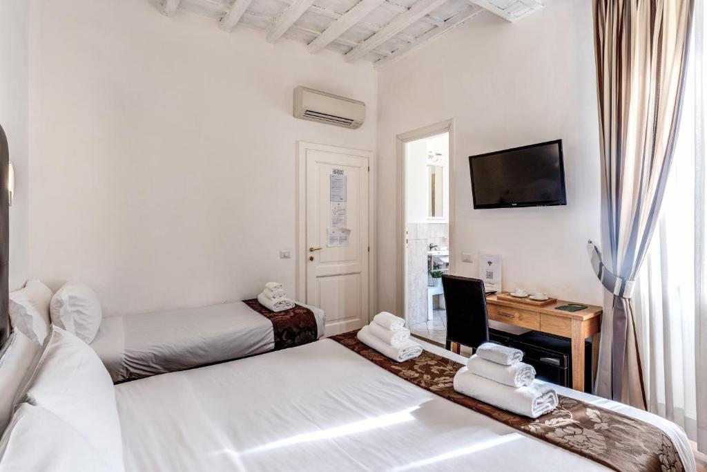 a bedroom with two beds and a desk and a television at Magenta Deluxe Cancello in Rome