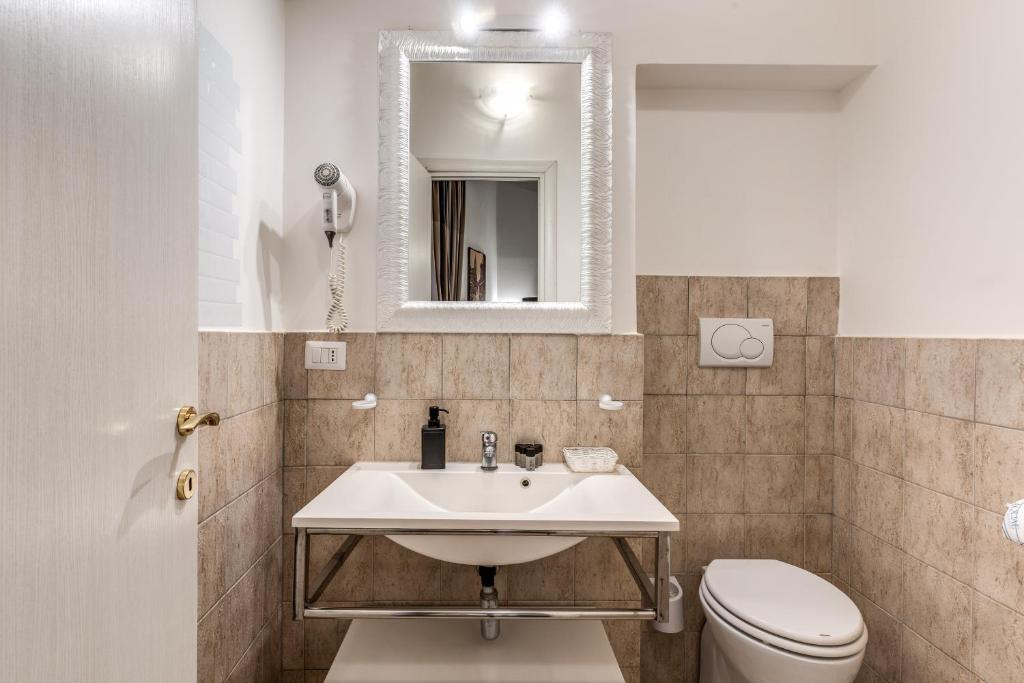 a bathroom with a sink and a toilet and a mirror at Magenta Deluxe Cancello in Rome