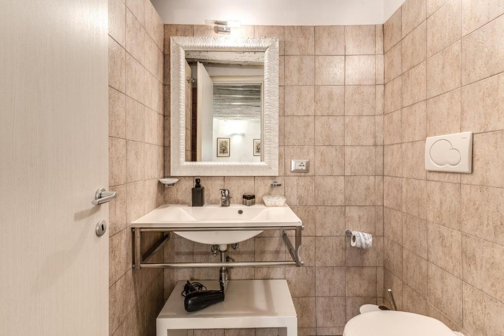 a bathroom with a sink and a toilet and a mirror at Magenta Deluxe Cancello in Rome