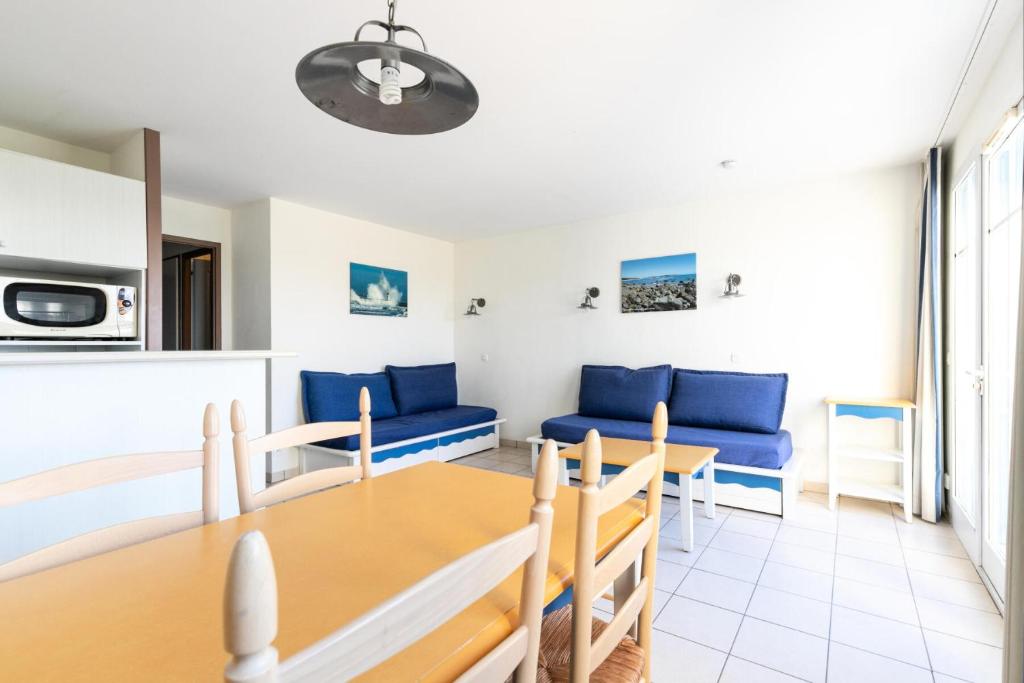 a living room with a dining room table and blue couch at Résidence Port Bourgenay - maeva Home - Appartement 3 Pièces 7 Personnes - 714 in Talmont
