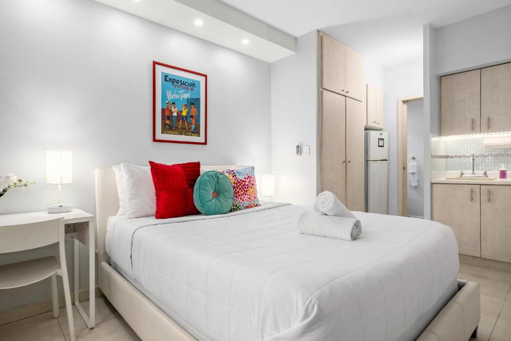 a white bedroom with a large bed and a kitchen at Prime Location at Condado Beach Queen Studio - Apt 10 in San Juan