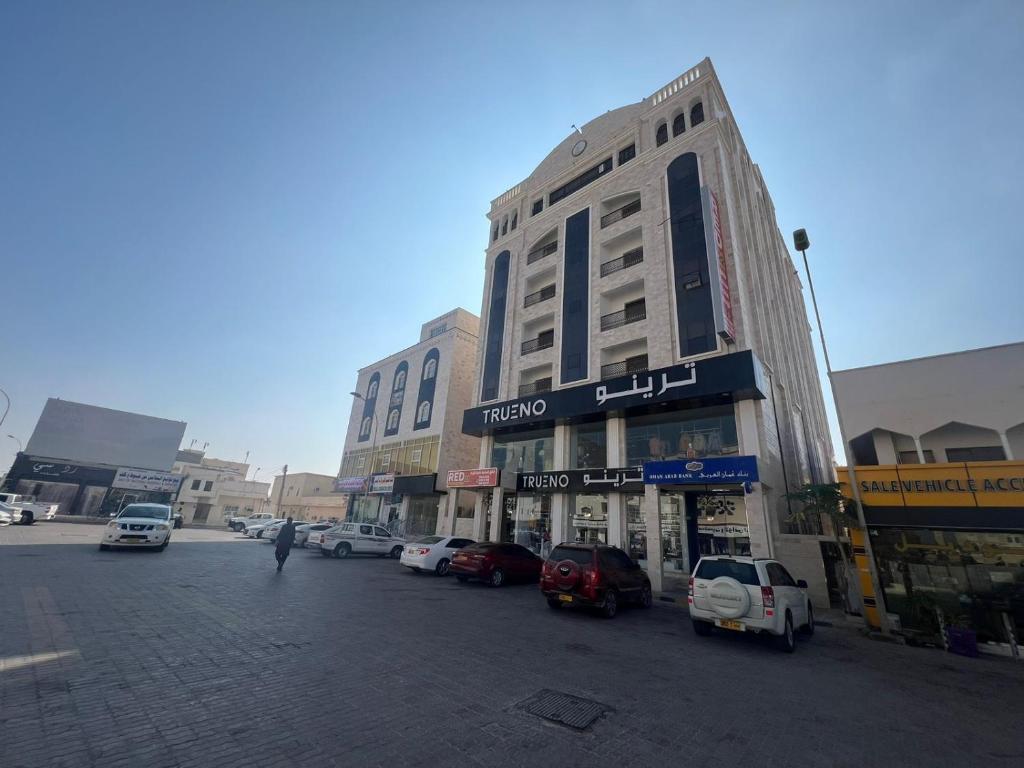 a building on a street with cars parked in front at RED-22- ALSALAM suites in Salalah