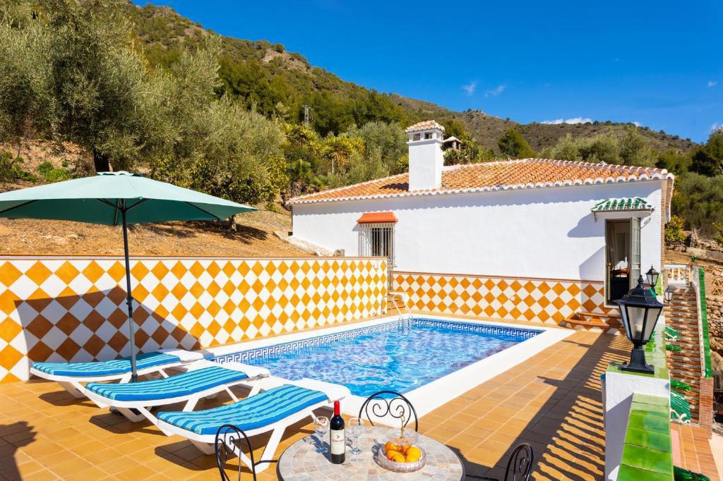 a swimming pool with two chairs and an umbrella at Villa Casa Leo in Frigiliana