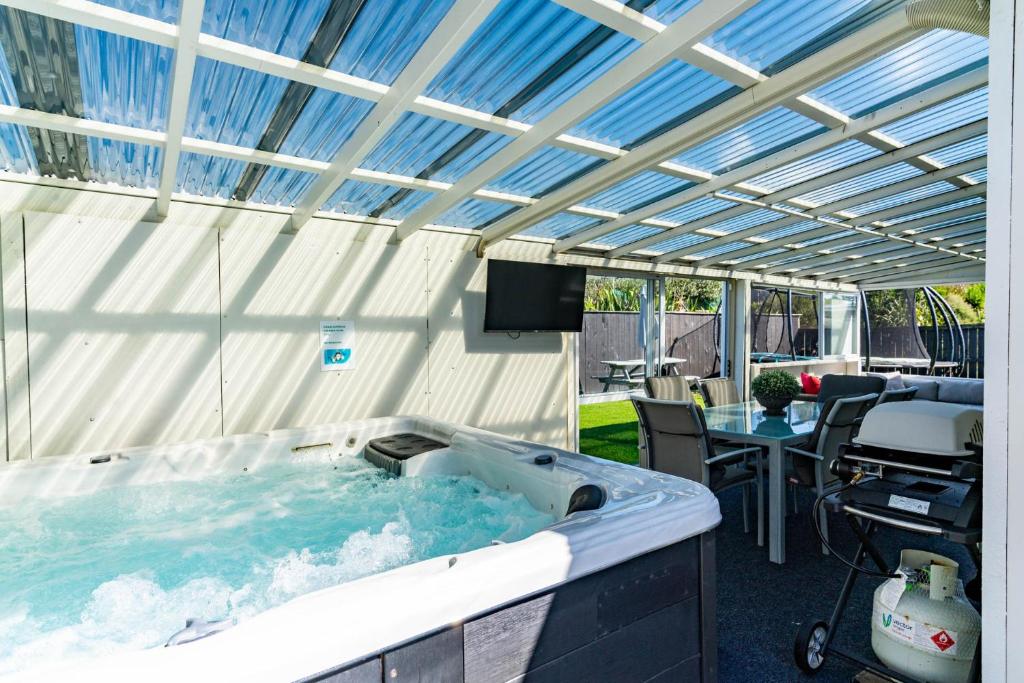 a hot tub in a patio with a roof at Sunnyside Spa Retreat - Mangawhai Holiday Home in Mangawhai