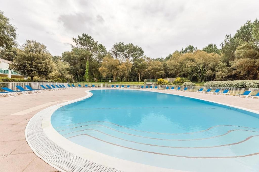 a large swimming pool with blue chairs and trees at Le Domaine du Golf de Pinsolle - maeva Home - Appartement 2 pièces 6 person 574 in Soustons