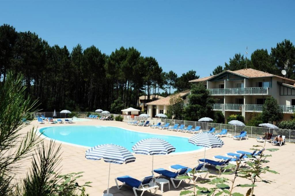 a pool with chairs and umbrellas and a resort at Le Domaine du Golf de Pinsolle - maeva Home - Appartement 2 pièces 6 person 574 in Soustons