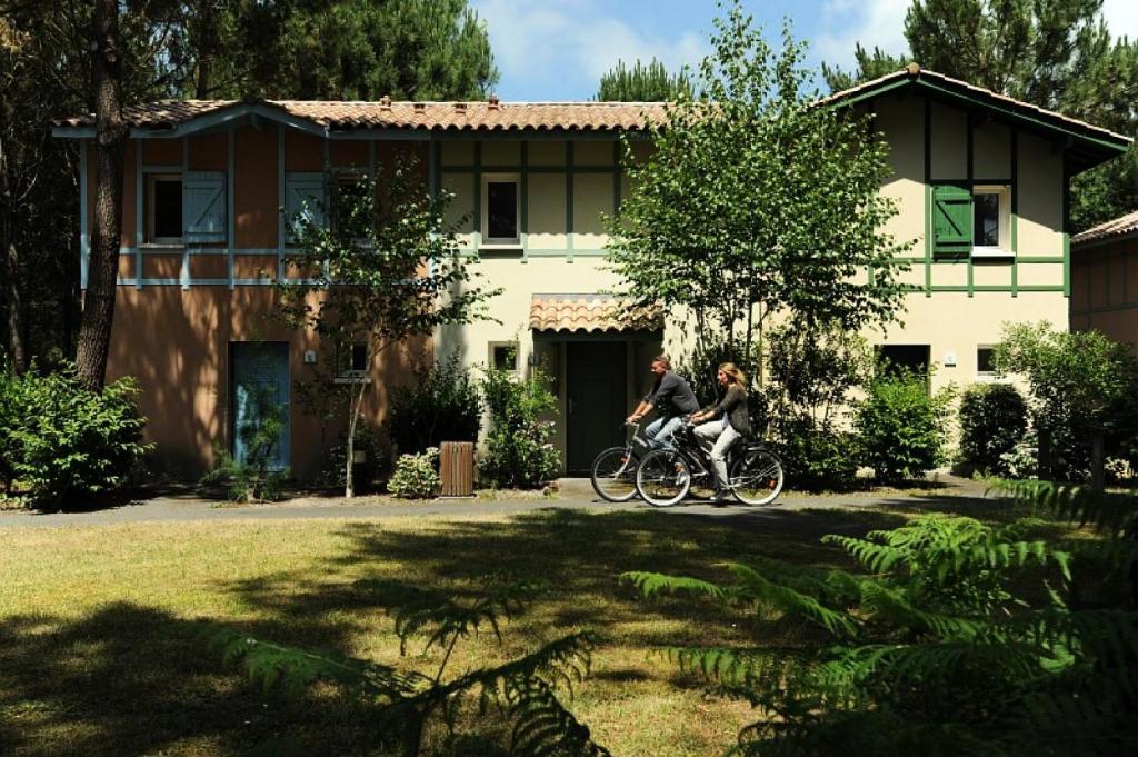 two people riding a bike in front of a house at Le Domaine du Golf de Pinsolle - maeva Home - Appartement 2 pièces 6 person 574 in Soustons