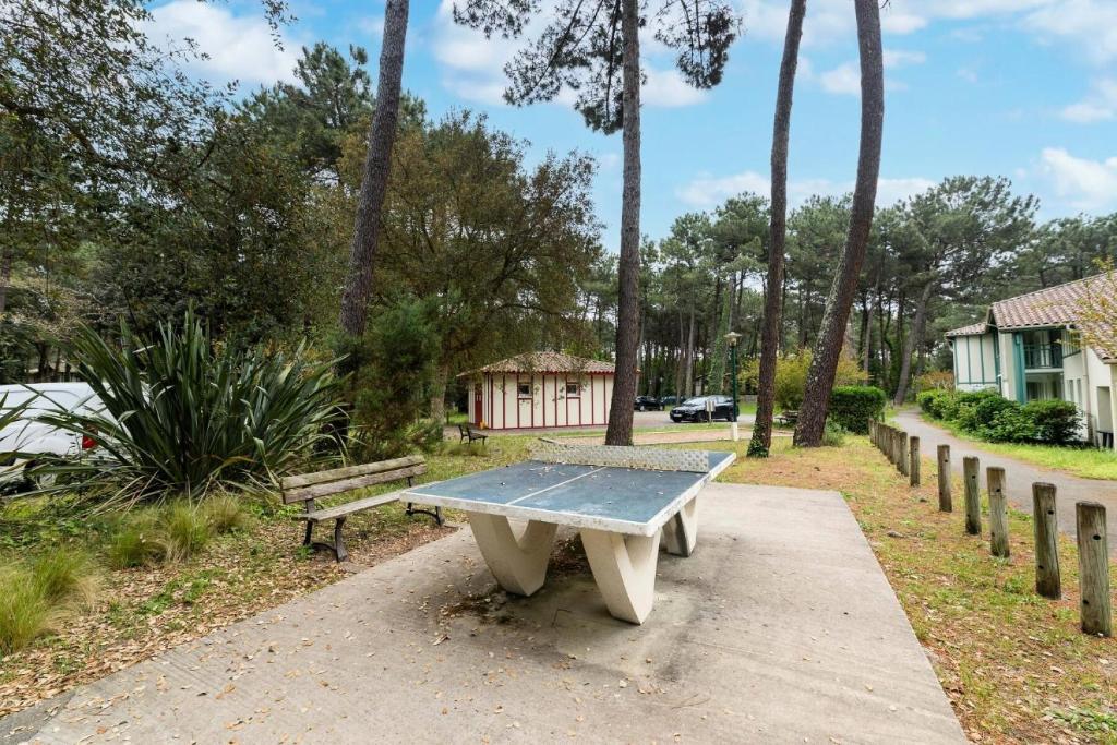 a bench sitting on a sidewalk in a park at Le Domaine du Golf de Pinsolle - maeva Home - Appartement 2 pièces 6 person 574 in Soustons