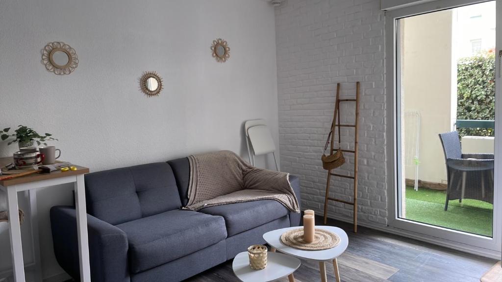 ein Wohnzimmer mit einem blauen Sofa und einem Fenster in der Unterkunft Studio Bayonne avec Piscine in Bayonne