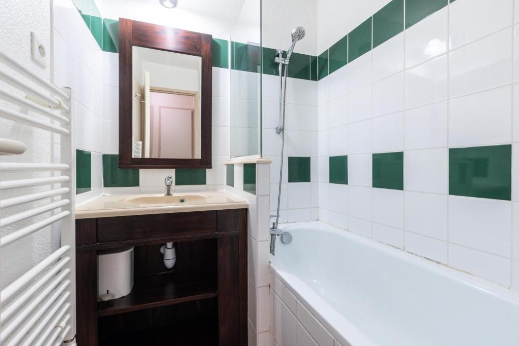 a bathroom with a sink and a mirror and a tub at Le Domaine du Golf de Pinsolle - maeva Home - Appartement 2 pièces 6 person 574 in Soustons
