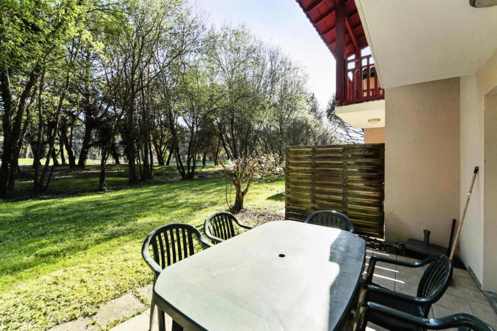 - une table et des chaises sur une terrasse avec vue sur la cour dans l'établissement Les Maisons du Domaine du Golf de Pinsolle - maeva Home - Maison 3 pièces 6 personnes - Confort MAE-6354, à Soustons