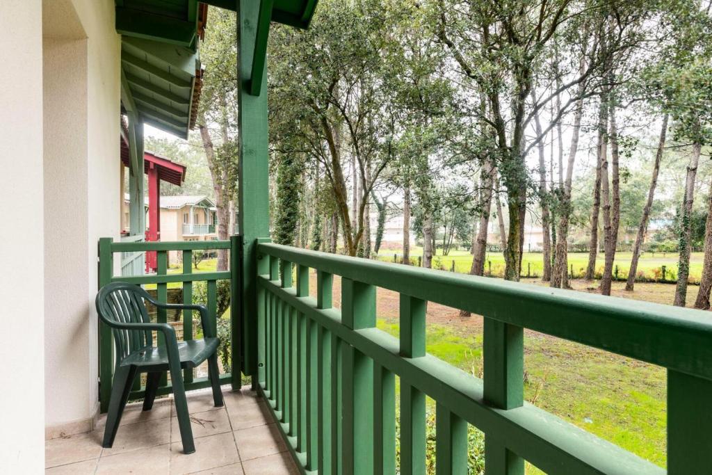 une chaise sur une terrasse couverte avec vue sur un champ dans l'établissement Les Maisons du Domaine du Golf de Pinsolle - maeva Home - Maison 3 pièces 6 personnes - Sélection MAE-6364, à Soustons