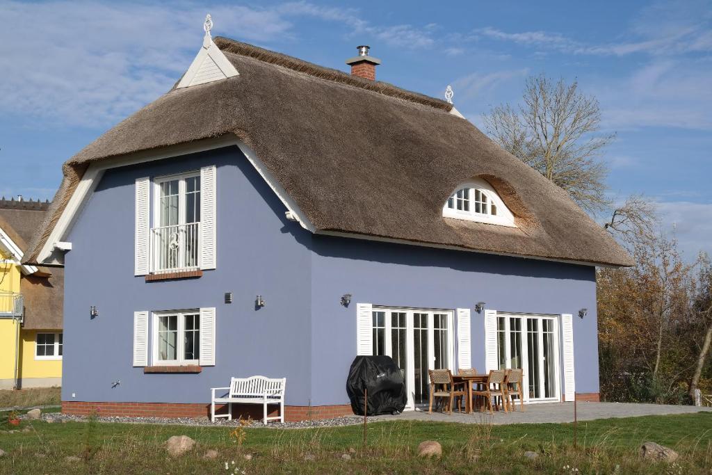 una casa azul con techo de paja en Ferienhaus Utkiek, en Poseritz
