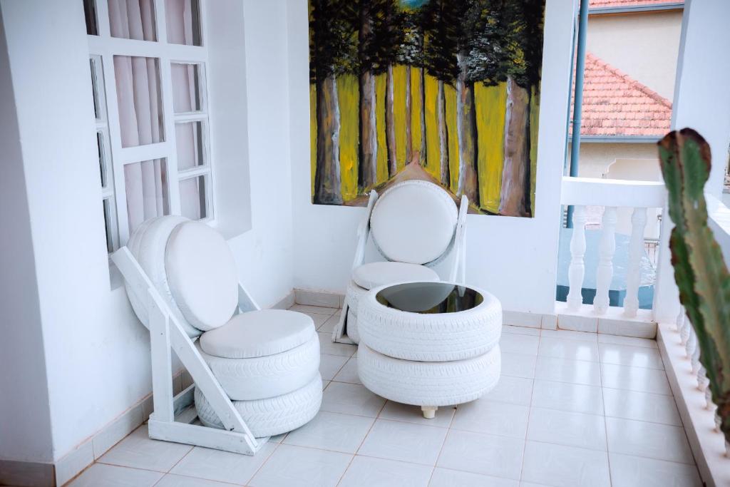 a room with two white chairs and a painting on the wall at Nina's Apartment in Kigali