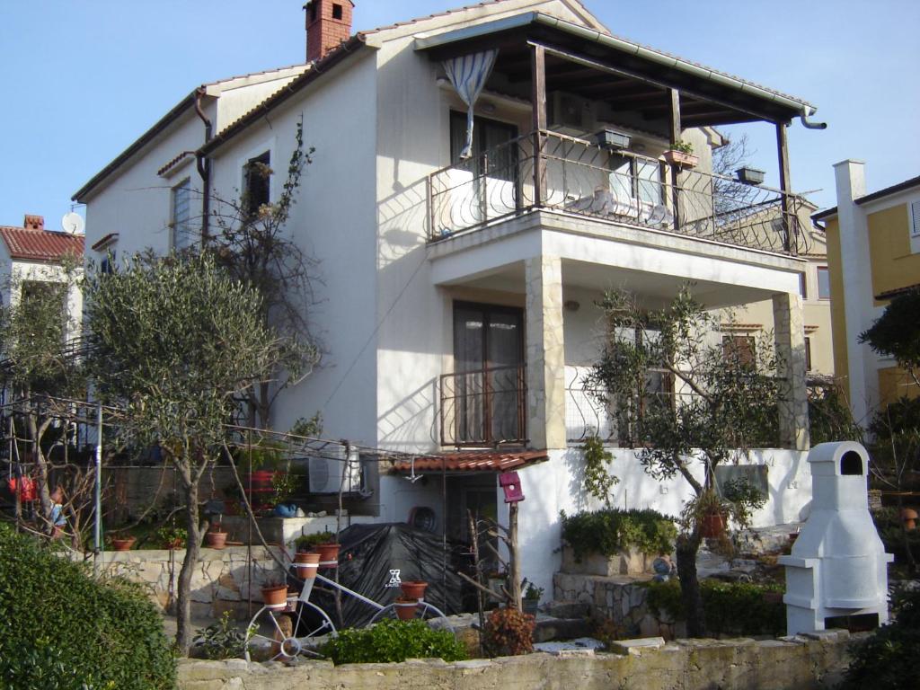 ein weißes Haus mit Balkon darüber in der Unterkunft Apartmani Sobe KATICA in Cres