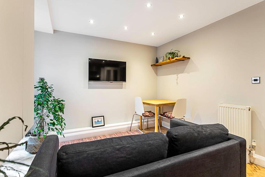 a living room with a couch and a flat screen tv at Cosy Garden Flat in Prestigious Residential Area in London