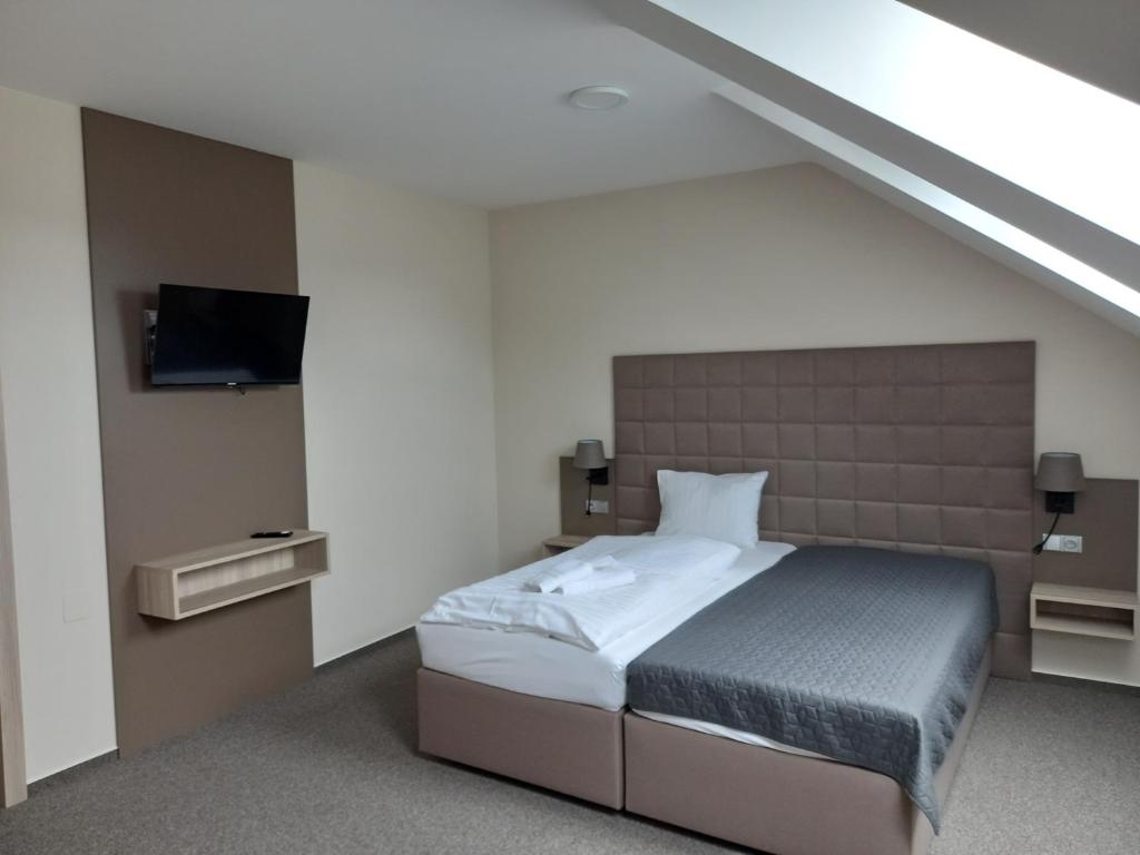 1 dormitorio con 1 cama y TV en Penzion a restaurace U Hroznu en Velké Bílovice