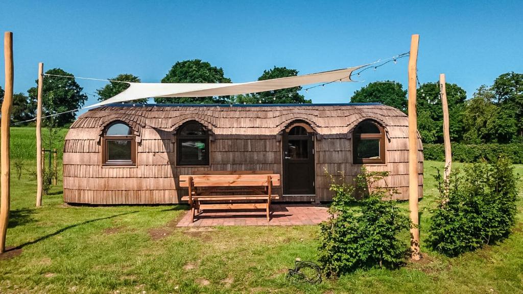 een houten schuur met een bank en een witte luifel bij Tiny Igloo Joergensen in Belau