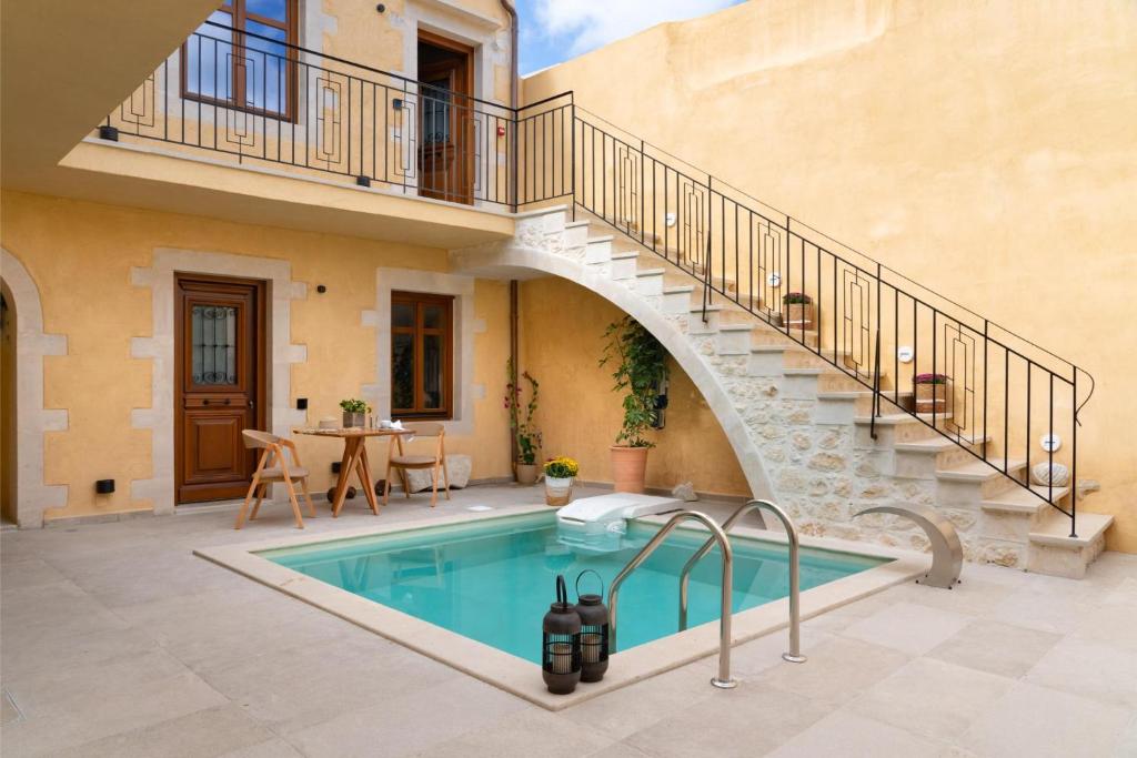 a swimming pool in a courtyard with a staircase next to a house at Mansio Boutique Hotel in Rethymno