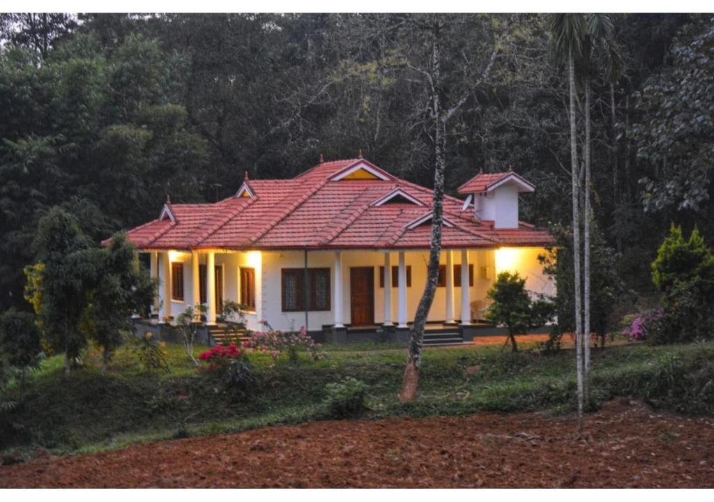 瓦亚纳德Spice Fields Cottage - 3 Bedroom - Wayanad的一间白色的小房子,有红色的屋顶