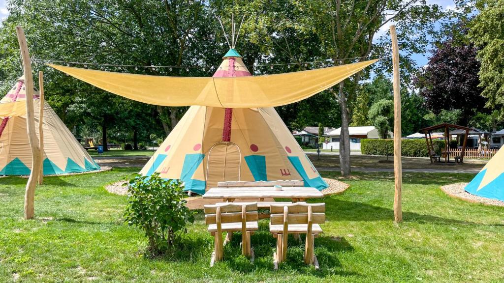 a teepee tent with a table and chairs in a park at Tipi Illinois in Falkenberg