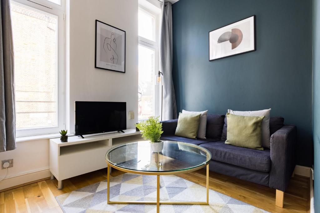 a living room with a blue couch and a glass table at The Whitecross Street Collection in London