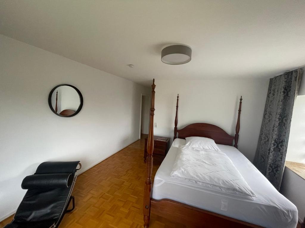 1 dormitorio con cama, espejo y silla en Ferienwohnung Wohnung Krefeld Forstwald Höltehoffe, en Krefeld