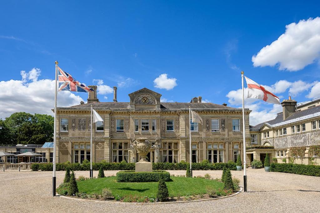 un grande edificio in pietra con bandiere di fronte di Down Hall Hotel a Bishops Stortford