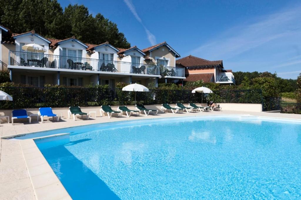 une piscine dans un hôtel avec des chaises et des parasols dans l'établissement Résidence Le Hameau du Lac - maeva Home - Appartement 2 pièces 4 personnes - Confort MAE-0524, à Marciac