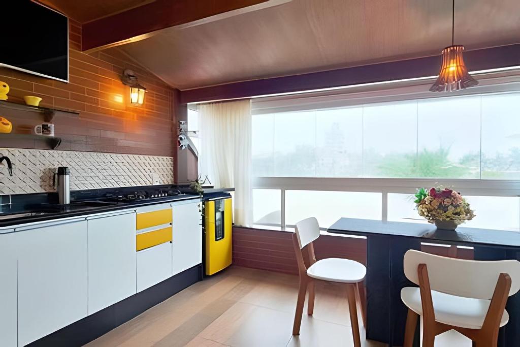 a kitchen with white cabinets and a table and chairs at Estada Inesquecível 17 Guarapari in Guarapari