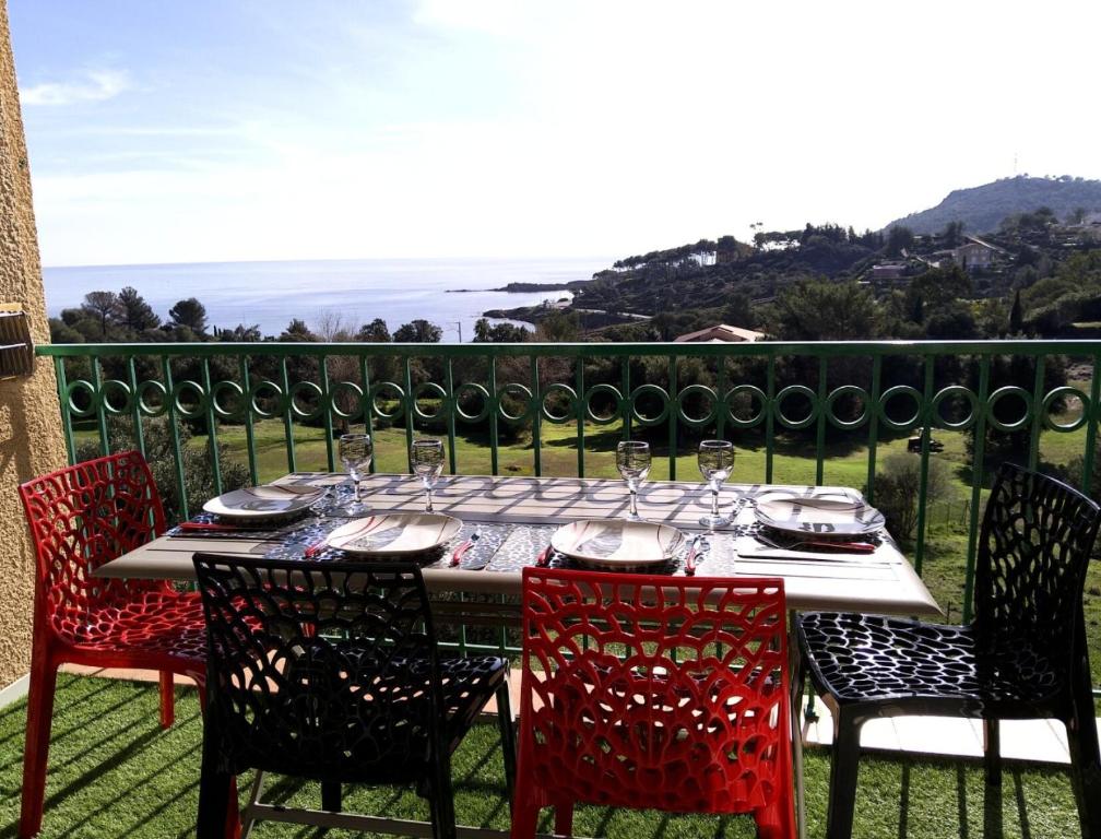 une table avec des chaises et des verres à vin sur un balcon dans l'établissement Résidence le Village de Cap Esterel - maeva Home - Appartement 2 pièces 5 personnes vue mer - Prestige - Super Home MAE-5574, à Saint-Raphaël